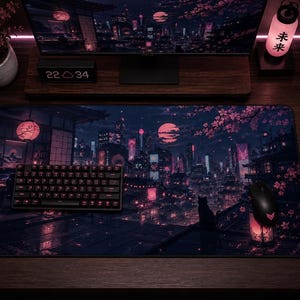 May include: A rectangular desk mat featuring a dark, atmospheric illustration of a Japanese-inspired cityscape at night with pink cherry blossoms, a large moon, and a silhouette of a cat sitting on a rooftop, with a black keyboard and mouse on top.