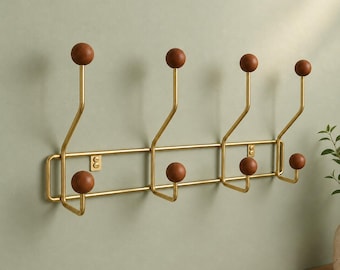 May include: A wall-mounted coat rack featuring a gold-toned metal frame with eight hooks. Each hook is finished with a round, dark brown wooden knob at the end. The rack has a horizontal rectangular structure with two parallel bars and mounting plates.