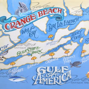 May include: A hand-painted map of Orange Beach and the Gulf of America featuring blue waterways, tan landmasses, and text labels for locations like Wolf Bay and Gulf State Park. Includes illustrations of dolphins, a pelican, a fish, and a seashell.