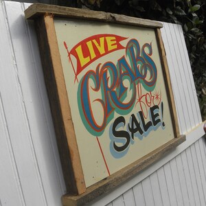 May include: A wooden framed sign with the text "LIVE CRABS for SALE!" painted in blue, red, yellow, and green on a cream background.