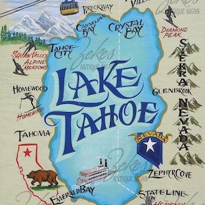 May include: A painted wooden sign featuring a map of Lake Tahoe in blue with surrounding text labels for locations like Incline Village, Tahoe City, and Emerald Bay. It includes illustrations of a ski lift, mountains, a bear, and a paddle boat.