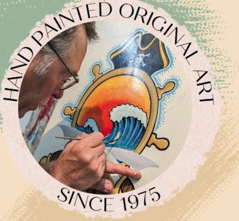 May include: A close-up of a person painting a nautical-themed artwork. The artwork features a ship's wheel, a wave, and a sunset. The text "HAND PAINTED ORIGINAL ART SINCE 1975" is visible around the artwork.