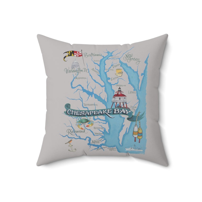May include: A decorative cushion with a light grey background featuring a blue and white illustration of the Chesapeake Bay. The illustration includes the names of cities and towns along the bay, as well as a lighthouse and buoys. The text "CHESAPEAKE BAY" is written in a decorative font.