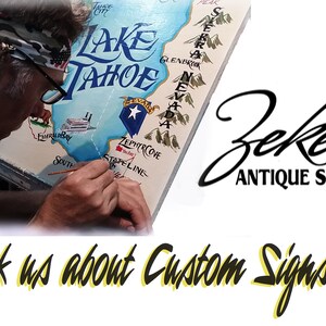 May include: A person paints a custom sign with a map of Lake Tahoe, California. The sign features the text "Lake Tahoe" and "Zekes Antique Signs". The text "ask us about Custom Signs!" is written in yellow and black.