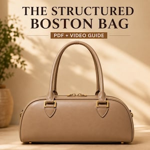 May include: A taupe-coloured structured Boston bag with dual top handles, gold-tone hardware, and a top zip closure. The text above the bag reads: THE STRUCTURED BOSTON BAG PDF + VIDEO GUIDE. The bag features a smooth finish and a rectangular base.