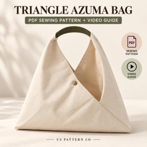Puede incluir: Un bolso triangular Azuma de color crema con un asa verde oscuro y un cierre de broche metálico. La imagen incluye el texto TRIANGLE AZUMA BAG, PDF SEWING PATTERN + VIDEO GUIDE, US PATTERN CO, junto con iconos de PDF y guía de vídeo.