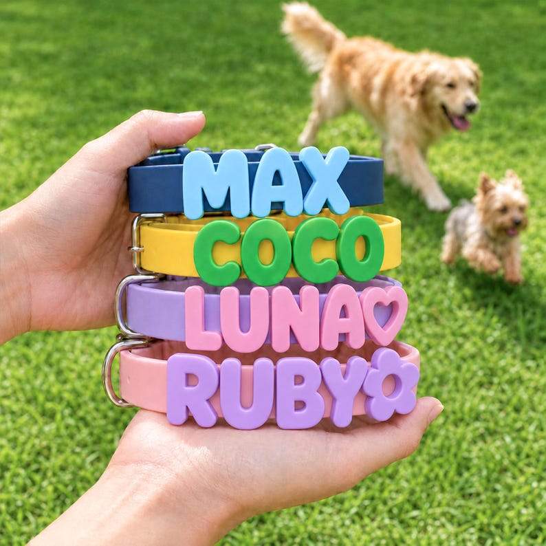 May include: A stack of four silicone pet collars in navy blue, yellow, lavender, and light pink. Each collar features large, raised, colorful letters spelling out the names MAX, COCO, LUNA, and RUBY, with a heart icon next to LUNA and a flower icon next to RUBY.