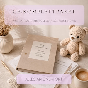 May include: A beige fabric-covered binder labelled CE-KOMPLETTPAKET with sub-labels for templates, risk analysis, checklists, and instructions. Beside it sits a crocheted beige teddy bear, a gold pen, a white vase with dried flowers, and a coffee mug.