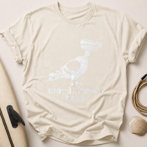 Cream t-shirt with pigeon graphic and "BIRDS AREN'T REAL" text.