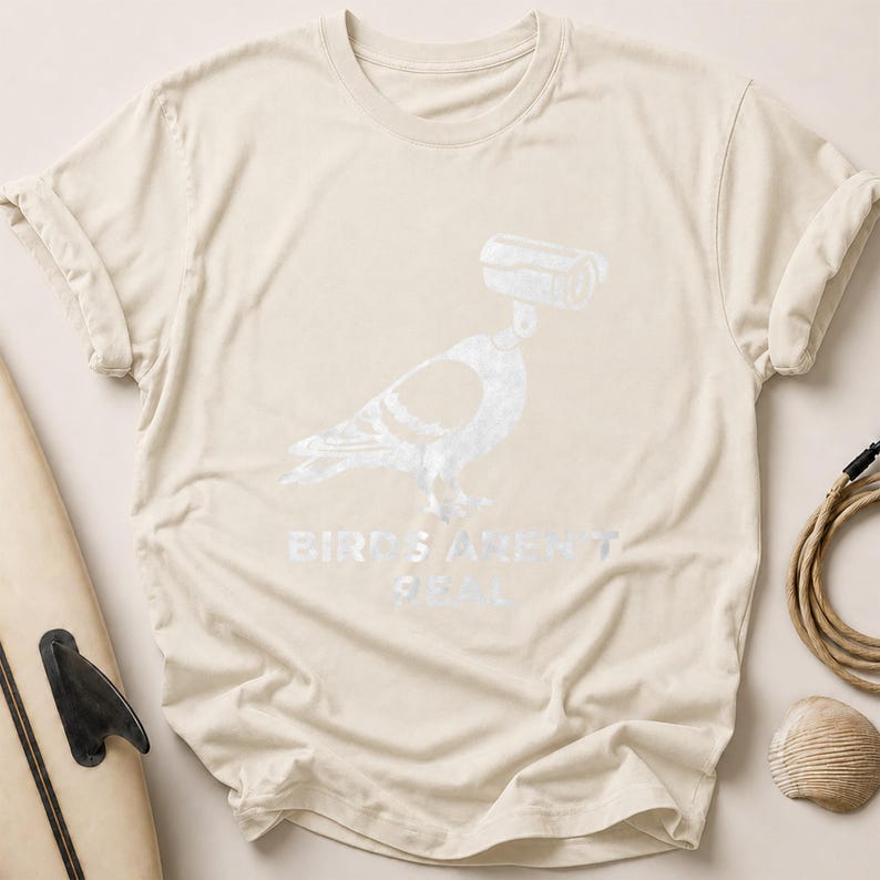 Cream t-shirt with pigeon graphic and "BIRDS AREN'T REAL" text.