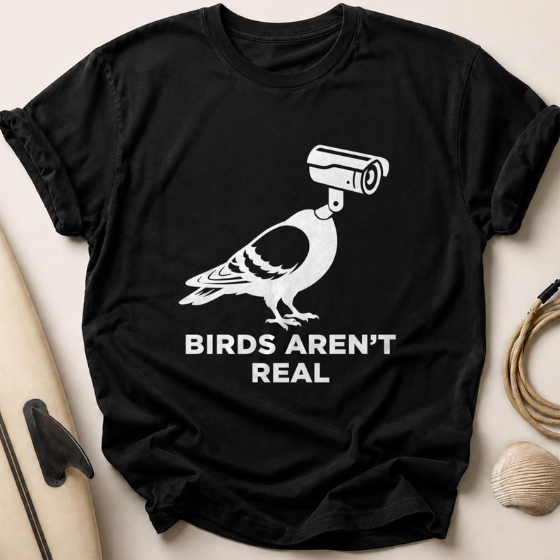 Black t-shirt with a white graphic of a pigeon wearing a security camera.