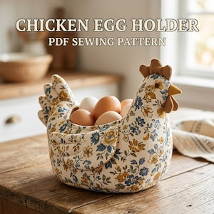 May include: A fabric chicken egg holder featuring a cream-colored base with a blue and yellow floral pattern. The chicken-shaped container has a brown comb and beak, and it holds several brown eggs. The text CHICKEN EGG HOLDER PDF SEWING PATTERN is visible.
