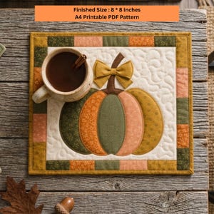 Peut inclure: Un tapis en tissu matelassé carré présentant une applique centrale en forme de citrouille avec un nœud jaune moutarde, entouré d'une bordure en patchwork dans des tons vert, orange et doré. La taille finie est de 20,32 par 20,32 cm.