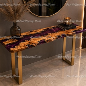 May include: A rectangular console table featuring a live-edge wood slab with a central deep purple resin river inlay. The table is supported by two U-shaped brushed gold metal legs. The surface displays natural wood grain patterns and textures.