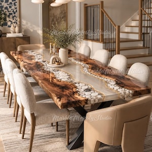 May include: A rectangular dining table featuring a live-edge wood slab with a central river of translucent resin embedded with smooth white stones. The table is supported by a black metal X-shaped base and surrounded by upholstered dining chairs.