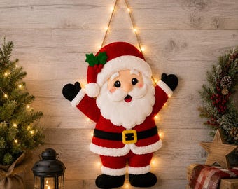 May include: A plush Santa Claus wall hanging featuring a red suit with white faux fur trim, a black belt with a yellow buckle, and black boots. The figure has a white beard, a red hat with green holly leaves, and is illuminated by string lights.