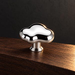 May include: A polished chrome cabinet knob featuring an irregular, cloud-like organic shape with a smooth, reflective surface. The knob has a cylindrical base that connects to a flared, circular mounting plate, creating a sleek, metallic appearance.