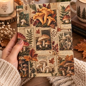 Pode incluir: Um diário de capa dura com uma colagem de selos de estilo vintage representando vários cogumelos, fetos e folhas de outono. A capa inclui textos como Wild Things, Nature Slows Us Down e Find Beauty In The Small Things.