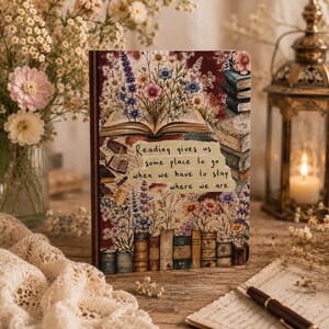 May include: A rectangular notebook featuring a floral and book-themed illustration with the text, Reading gives us some place to go when we have to stay where we are. The cover displays an open book with wildflowers and a stack of books.
