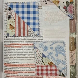 May include: Three triangular fabric page markers with pinked edges, featuring blue gingham, red and white stripes, and floral patterns. These markers are placed on the pages of an open book with printed text and handwritten notes in orange ink.