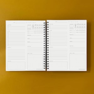 Puede incluir: Una agenda blanca con una encuadernaci&oacute;n en espiral negra. La agenda tiene secciones para tareas diarias, seguimiento de la hidrataci&oacute;n, estado de &aacute;nimo, sue&ntilde;o, energ&iacute;a, estr&eacute;s, notas y bienestar. La agenda est&aacute; abierta en dos p&aacute;ginas, ambas con el mismo dise&ntilde;o.