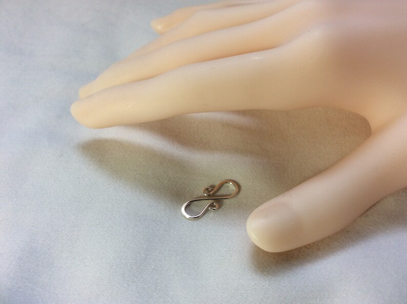 Puede incluir: Un cierre de s&iacute;mbolo de infinito de plata con un acabado liso y pulido. El cierre est&aacute; dise&ntilde;ado para ser utilizado en la fabricaci&oacute;n de joyas.