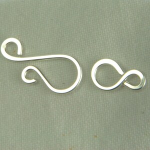 May include: Silver-toned metal clasp with a loop and a figure eight design. The clasp is used for jewelry making.