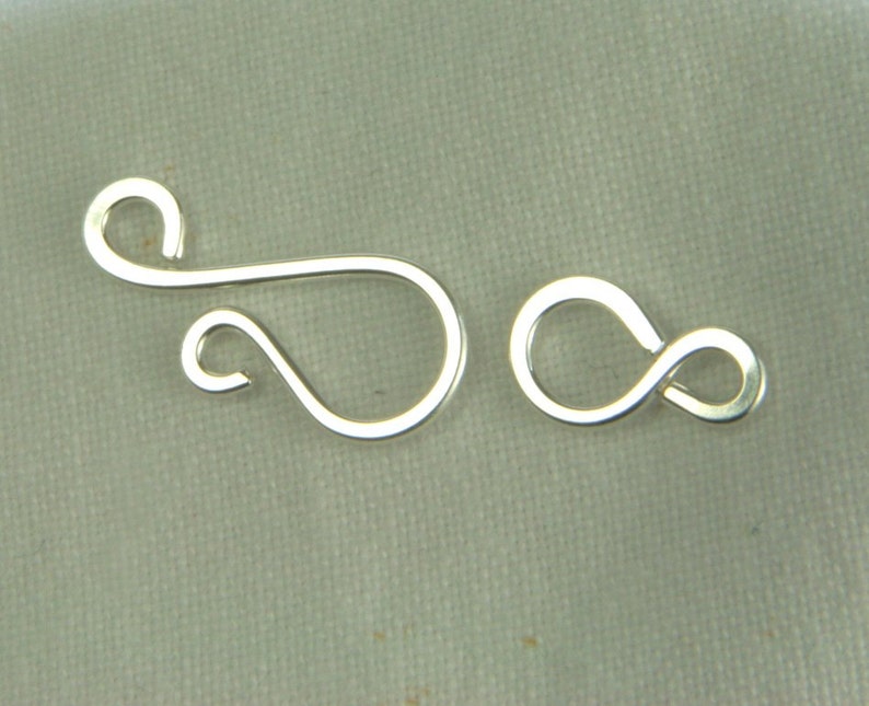 May include: Silver-toned metal clasp with a loop and a figure eight design. The clasp is used for jewelry making.
