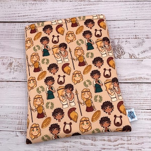 May include: A beige book sleeve featuring a repeating pattern of cartoon illustrations. The pattern includes figures in ancient Greek attire, helmets, shields, lyres, and laurel wreaths. A small blue tag is visible on the bottom right corner.