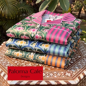 May include: A stack of three button-down pajama shirts featuring floral patterns and contrasting striped pockets. The top shirt is pink and green with pink flowers, the middle is blue with yellow flowers, and the bottom is orange with yellow flowers.