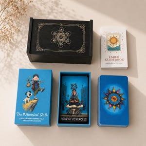 Può includere: Un set di carte dei tarocchi che include una scatola di legno nera con un design geometrico dorato, una guida bianca con un'illustrazione del sole e carte dai toni blu. Una carta mostra un personaggio con un cane, intitolata The Whimsical Path, e un'altra mostra una figura seduta su una struttura in pietra, etichettata Four of Pentacles.