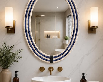 May include: An oval wall mirror featuring a frame wrapped in thick, alternating bands of cream and navy blue rope. The rope is secured at the top and bottom by small, black rectangular accents, creating a textured, nautical-inspired border.