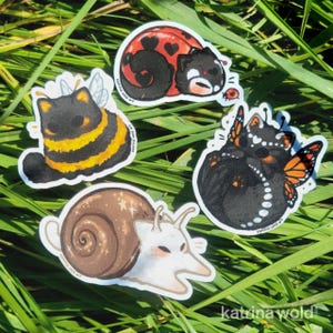 May include: Four die-cut stickers featuring stylized creatures: a black and yellow bumblebee cat, a red and black ladybug cat with heart spots, a black butterfly cat with orange wings, and a white snail cat with a brown shell.
