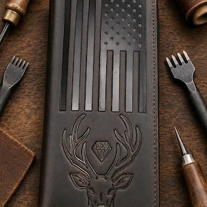 May include: A dark brown leather long wallet featuring an embossed American flag design on the upper portion and an embossed deer head with a diamond shape between the antlers on the lower portion, finished with visible perimeter stitching.