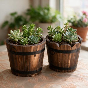 May include: Two round wooden planters with dark brown wood grain and black metal bands, each containing a variety of green succulent plants. The planters have a barrel-like construction with visible vertical slats and small metal ring handles.