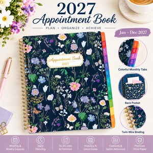 May include: A 2027 appointment book with a dark blue cover featuring a colorful floral and butterfly pattern. It includes gold twin-wire binding, monthly tabs, a back pocket, and a central label reading Appointment Book 2027.