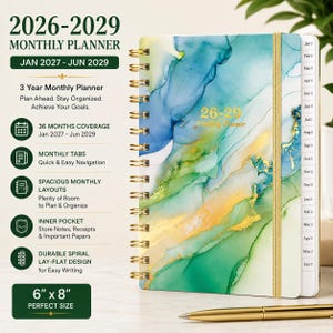 May include: A 6 inch by 8 inch monthly planner for 2026-2029 with a gold spiral binding and an elastic closure. The cover features an abstract blue, green, and gold ink wash design. It includes monthly tabs, an inner pocket, and 36 months of coverage from January 2027 to June 2029.