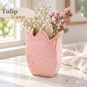May include: A pink ceramic tulip-shaped vase with a speckled texture, containing white and pink baby's breath flowers. The text Tulip Vase is visible in the upper left corner, and a digital template icon is in the upper right.
