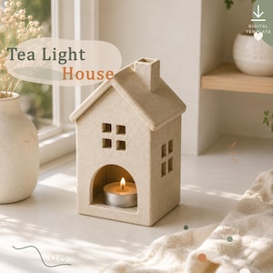 May include: A beige speckled ceramic tea light house with a gabled roof, a chimney, and square cut-out windows. The front features an arched opening containing a lit tea light candle. The text "Tea Light House" is visible in the upper left corner.