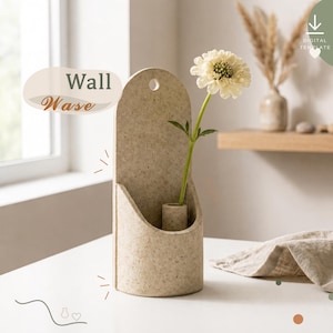 May include: A beige speckled wall vase with a rounded top and a single circular hanging hole. The vase features a cylindrical holder for a single stem and contains a white flower. The text "Wall Vase" is visible on the left side of the image.