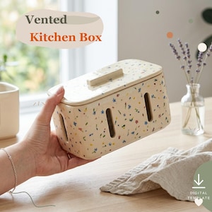 May include: A rectangular ceramic kitchen box with a cream-colored base featuring a multicolored floral speckle pattern. The box includes a matching lid and vertical ventilation slots on the sides. Text reads Vented Kitchen Box.