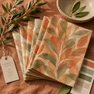 May include: A stack of fabric swatches featuring a botanical leaf pattern in shades of terracotta, sage green, and cream. A rectangular paper tag labeled Formfolk Studio is attached, and a color palette card shows terracotta, olive, warm beige, and soft cream.