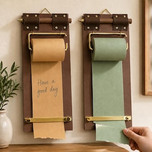 Peut inclure: Deux distributeurs de papier muraux avec des supports en bois brun foncé, des fixations en métal doré et des tiges en bois sombre. L'un contient un rouleau de papier beige avec le texte Have a good day, l'autre un rouleau vert sauge.