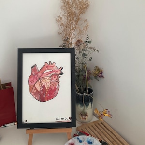 Peut inclure: Une illustration anatomique du cœur encadrée dans des tons de rouge et de rose, avec le texte AS-TU DU COEUR? en bas. L'œuvre est présentée sur un petit chevalet en bois, montrant une représentation détaillée de l'organe cardiaque humain.