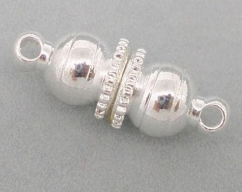Può includere: Una chiusura magnetica per gioielli color argento caratterizzata da due estremità sferiche lisce con un punto di connessione centrale scanalato e testurizzato. Ogni estremità della chiusura include un piccolo anello circolare per fissare gioielli.