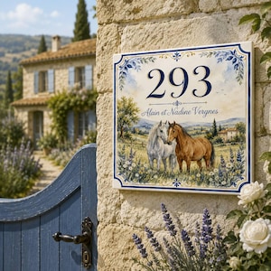 Puede incluir: Un letrero de casa cuadrado de cerámica con el número 293 y el texto Alain et Nadine Vergnes. El diseño muestra un paisaje pintado con un caballo blanco y uno marrón en un campo de flores, enmarcado por un borde de color azul y dorado.