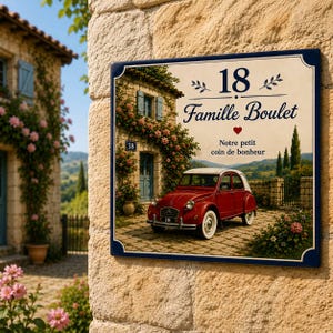 Op de afbeelding: Een rechthoekig naambord met een donkerblauwe rand, voorzien van het nummer 18, de tekst Famille Boulet en de zin Notre petit coin de bonheur. De illustratie toont een rode oldtimer geparkeerd voor een stenen huis met bloemen.