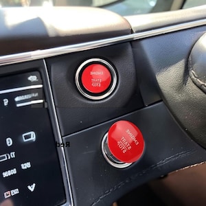 May include: A circular red engine start stop button cover with white text reading ENGINE START STOP. The cover is shown installed on a vehicle dashboard button and also as a separate piece placed over the existing ignition button.