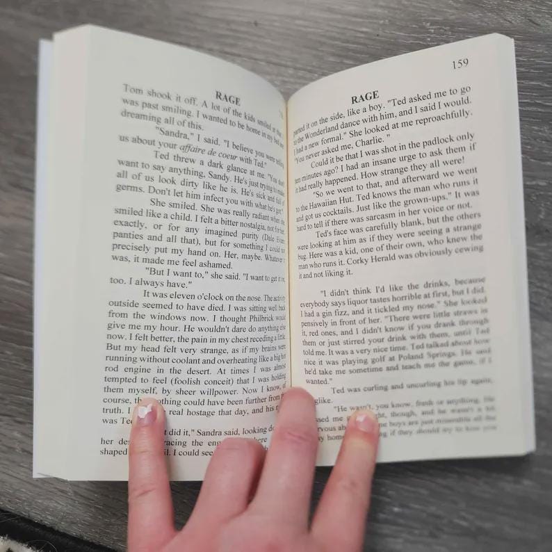 Puede incluir: Un libro abierto con p&aacute;ginas blancas y texto impreso en negro. La p&aacute;gina de la izquierda est&aacute; titulada RAGE y contiene varios p&aacute;rrafos de prosa narrativa. La p&aacute;gina de la derecha tambi&eacute;n est&aacute; titulada RAGE y muestra el n&uacute;mero de p&aacute;gina 159.
