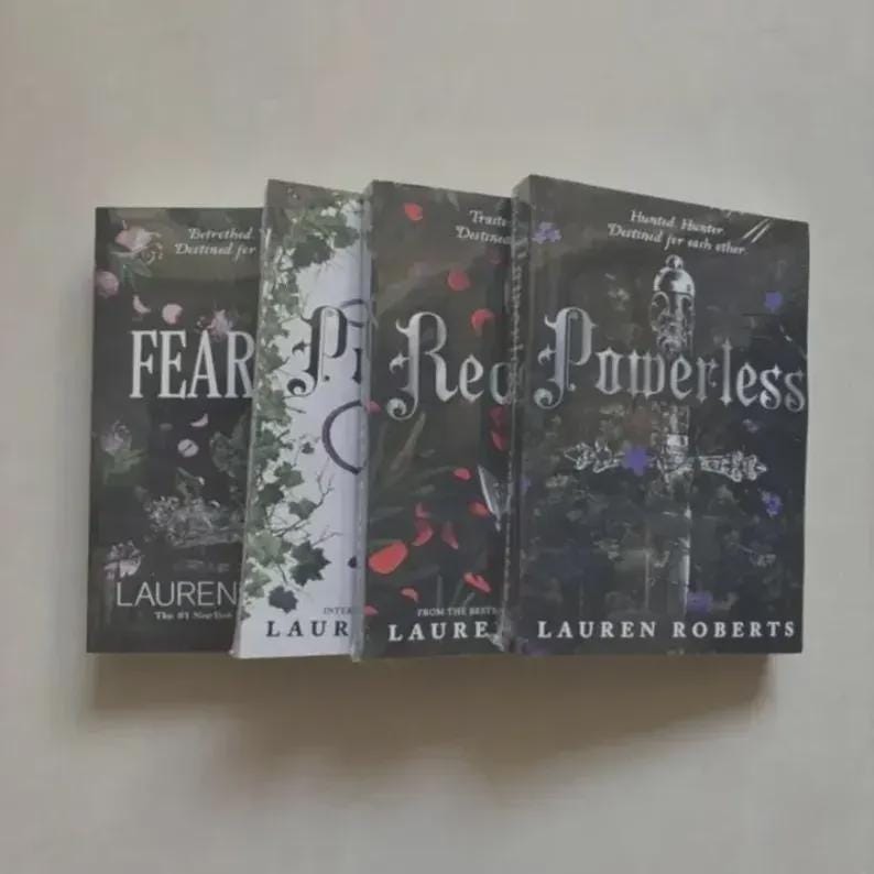 May include: A set of four books by Lauren Roberts arranged side-by-side. The covers feature dark and light floral and sword illustrations with the titles Fear, Powerless, and other text clearly visible in white and black serif and script fonts.